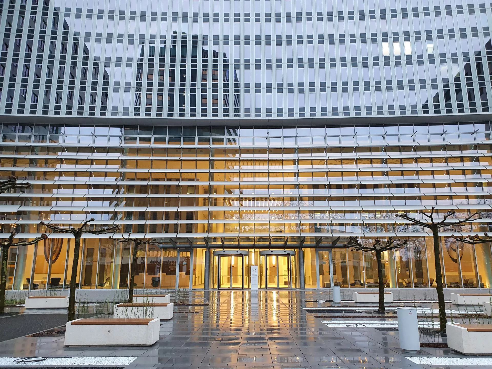 Façade vitrée éclairée au crépuscule avec accès sécurisés d’un bâtiment tertiaire